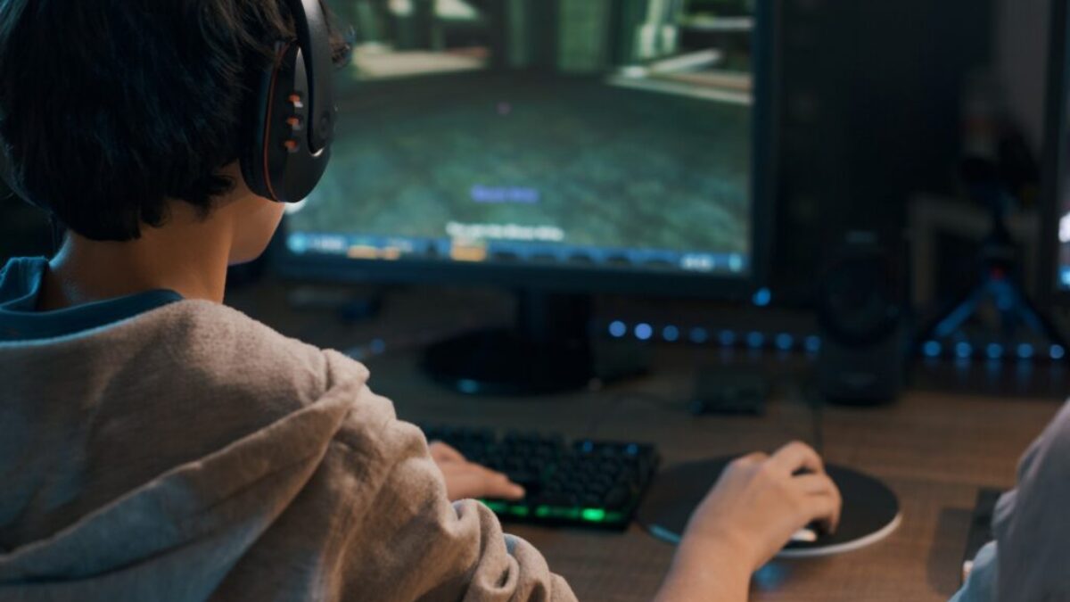 Teenager wearing a headset and playing online video games at home, 3D shooter games