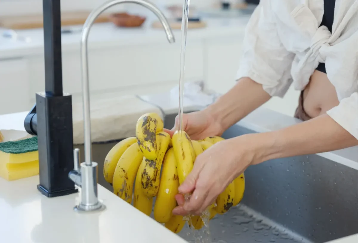 žena myje banány pod tekoucí vodou