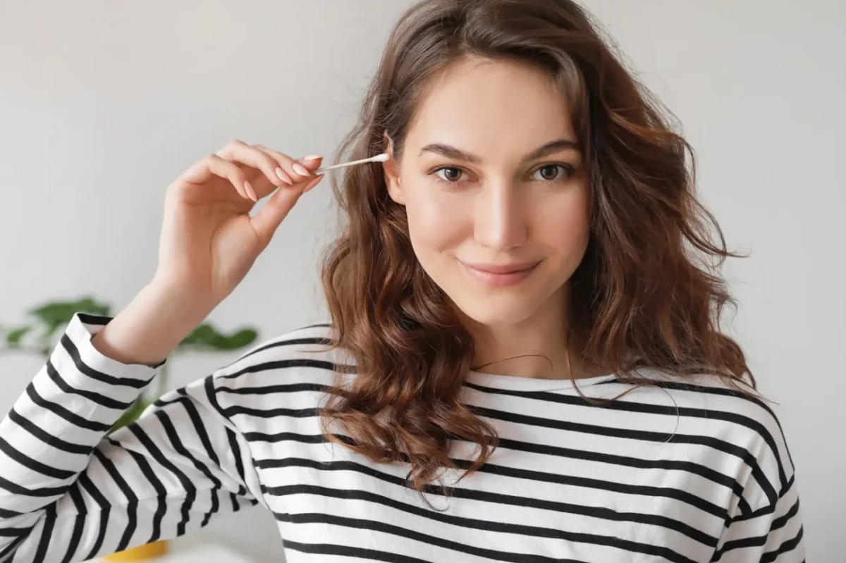 žena drží vatovou tyčinku u ucha