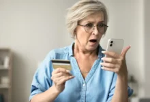 Udivená starší žena s mobilem a platební kartou