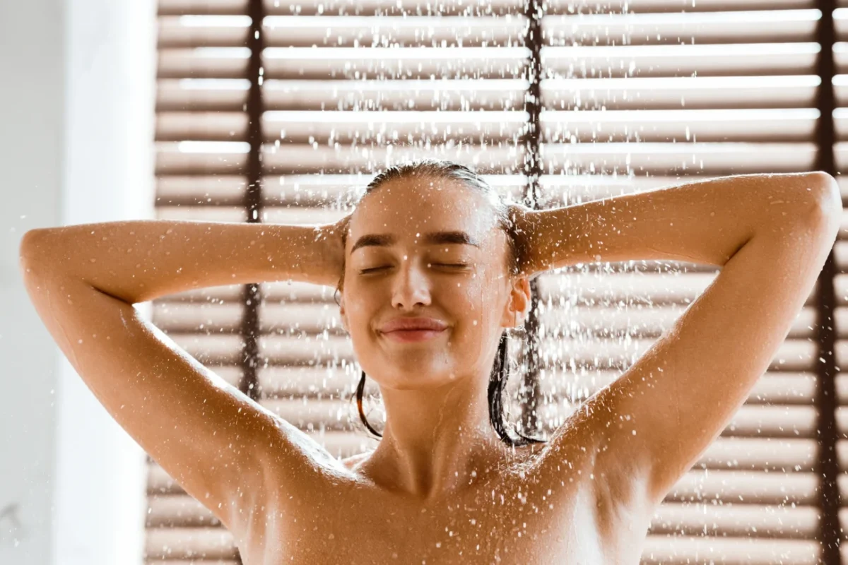 Žena, která si myje vlasy ve sprše.