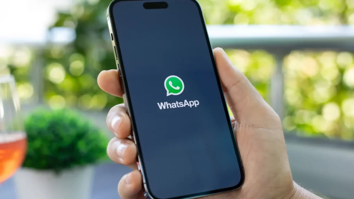 Ruka držící telefon s načítající se aplikací WhatsApp