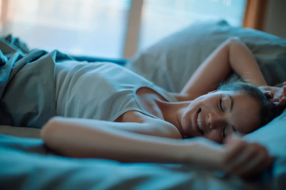 mladá žena se spokojeně usmívá v posteli
