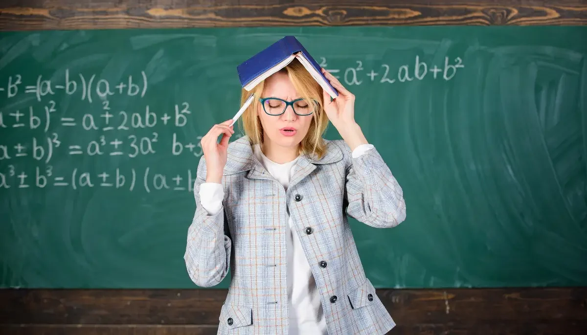 Žena před popsanou tabulí s knihou na hlavě