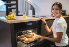 Mladá žena se usmívá a drží v ruce plech s croissanty.
