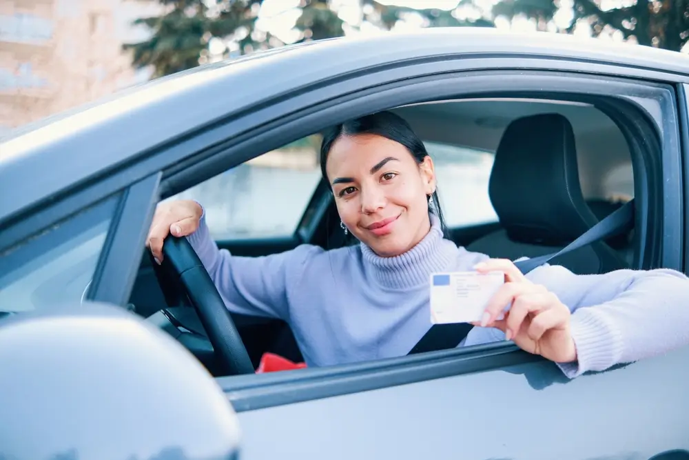 Žena drží v ruce řidičský průkaz.