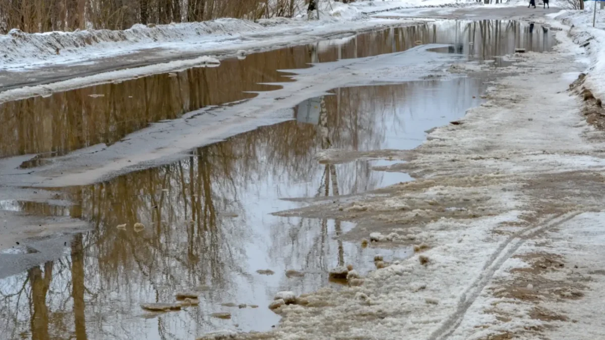 Silnice s tajícím sněhem a kalužemi