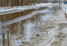 Silnice s tajícím sněhem a kalužemi