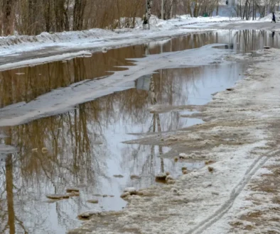 Silnice s tajícím sněhem a kalužemi
