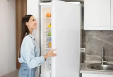 Mladá žena hledí do otevřené lednice.