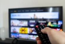 Ruka s ovladačem na televizi.