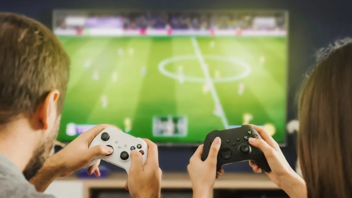 Pár sedí před televizí a hraje Xbox.