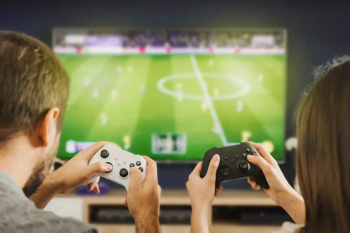 Pár sedí před televizí a hraje Xbox.