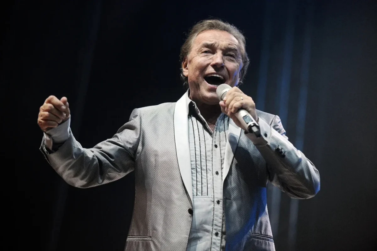 Karel Gott v obleku s mikrofonem v ruce.