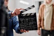 Filmová klapka a v pozadí herec.