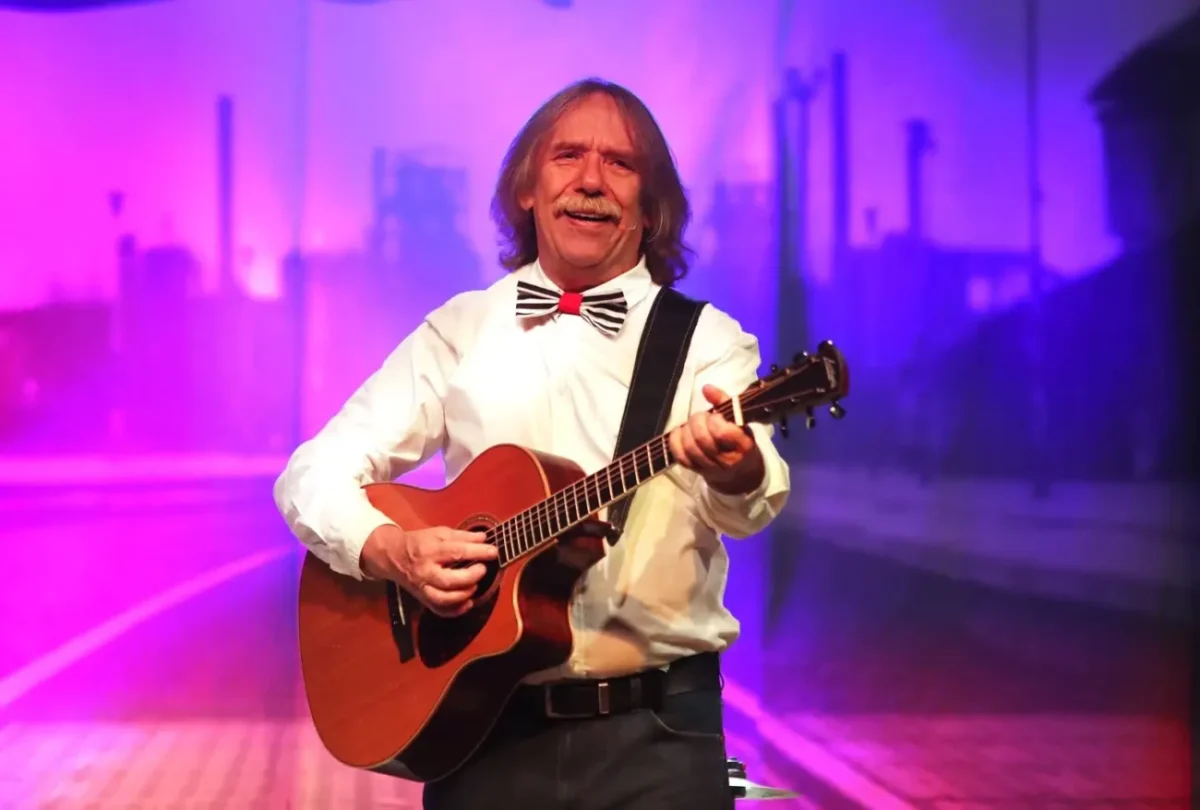 Zpěvák s kytarou v ruce vystupuje.