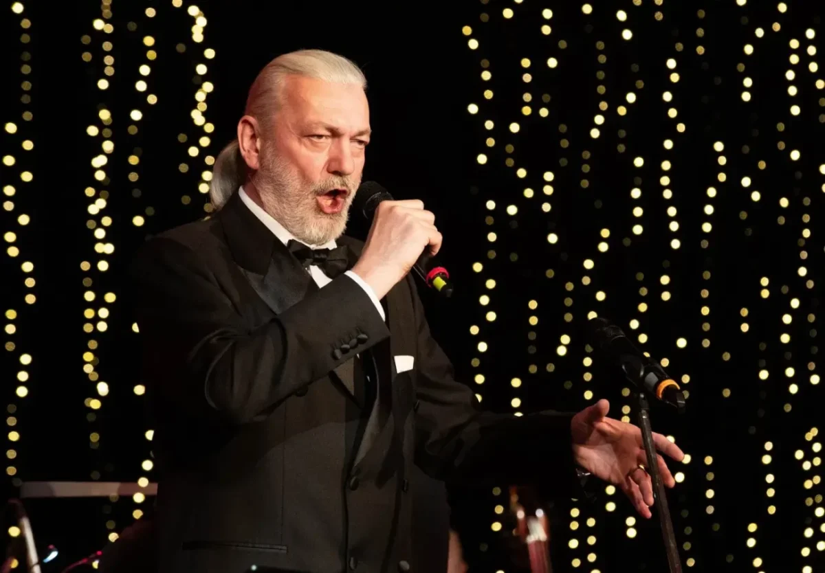 Zpěvák v černém saku s mikrofonem v ruce.