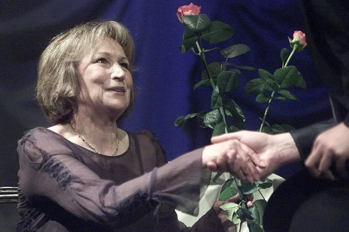 Žena ve slavnostním oblečení přebírá květiny.