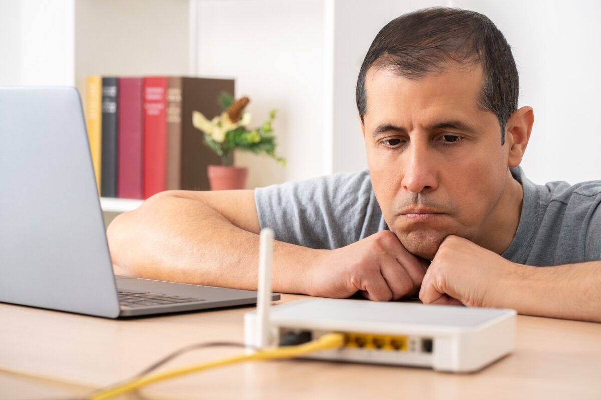 Muž opřený o stůl kouká na router.
