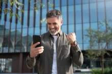 Muž se raduje a kouká se do telefonu.