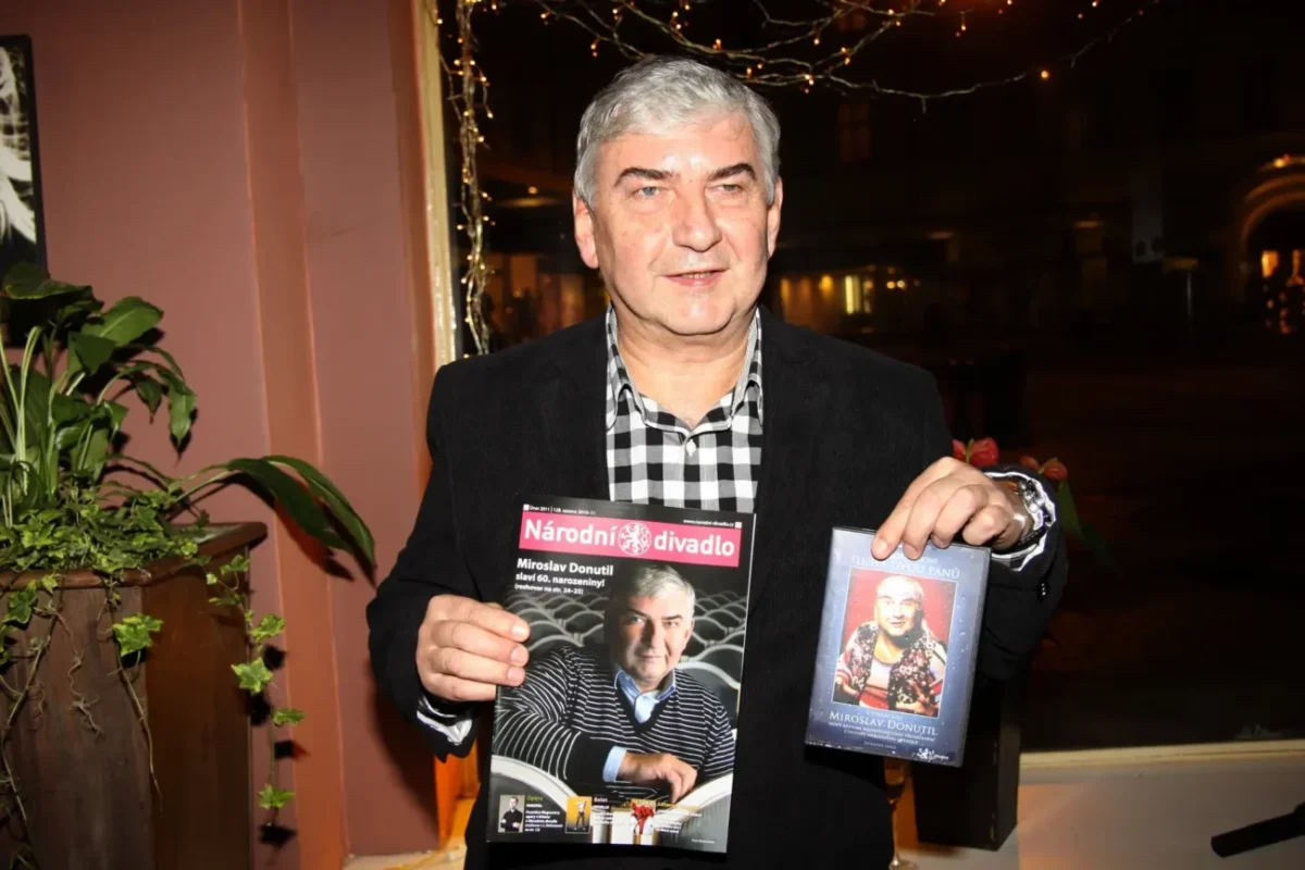 Muž drží v ruce časopis a knihu.