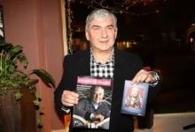 Muž drží v ruce časopis a knihu.