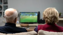 starý pár společně kouká z gauče na televizi