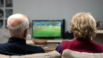 starý pár společně kouká z gauče na televizi
