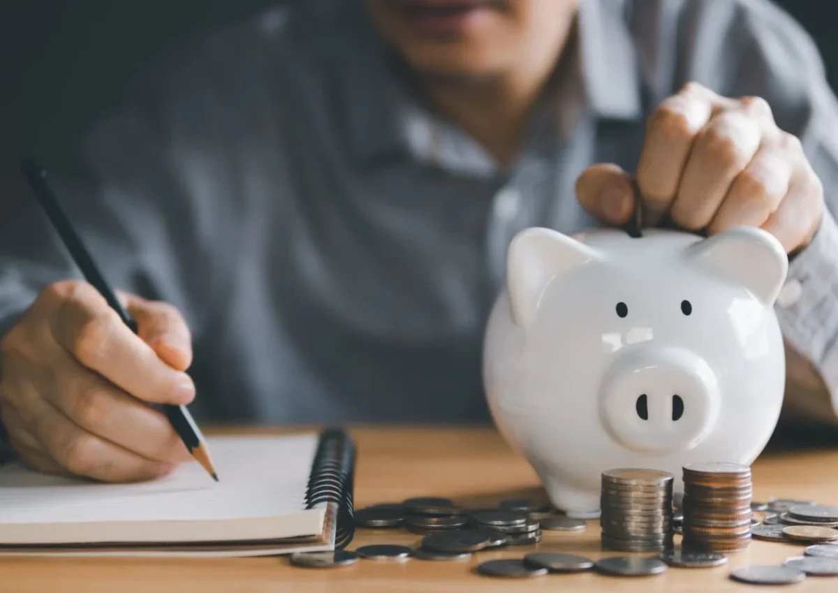 Muž počítající peníze do prasátka.