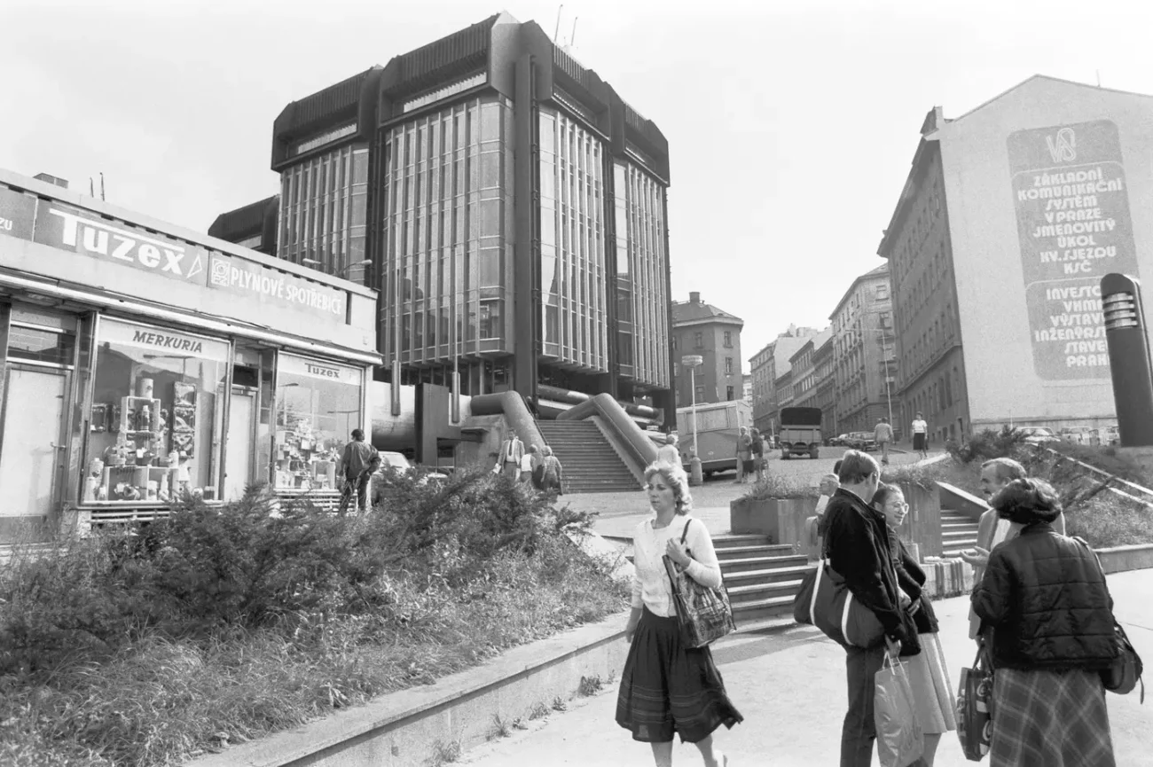 osoby procházející na ulici před prodejnou Tuzex