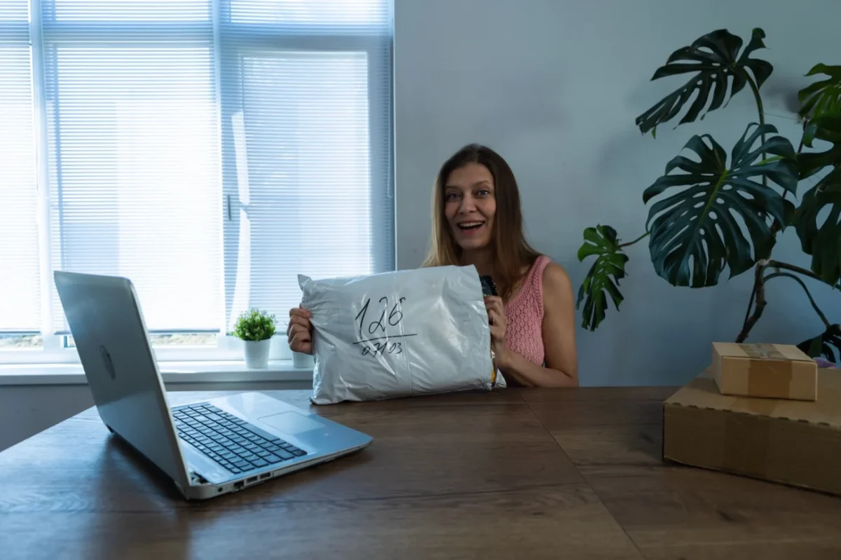 Žena sedí před notebookem s balíčkem.