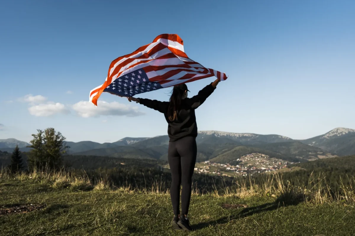 Žena v přírodě s americkou vlajkou.