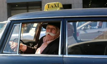 starý taxikář s knírem haleká z auta