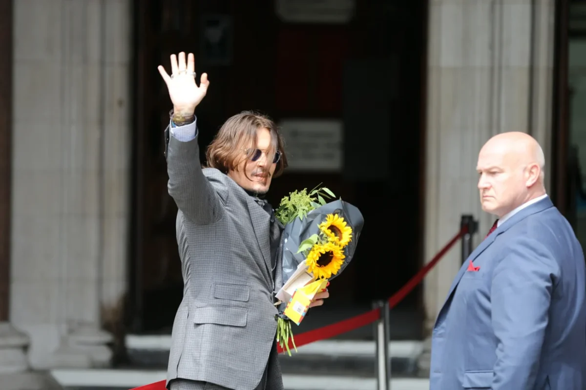 Johnny Depp mává a v ruce drží kytici.