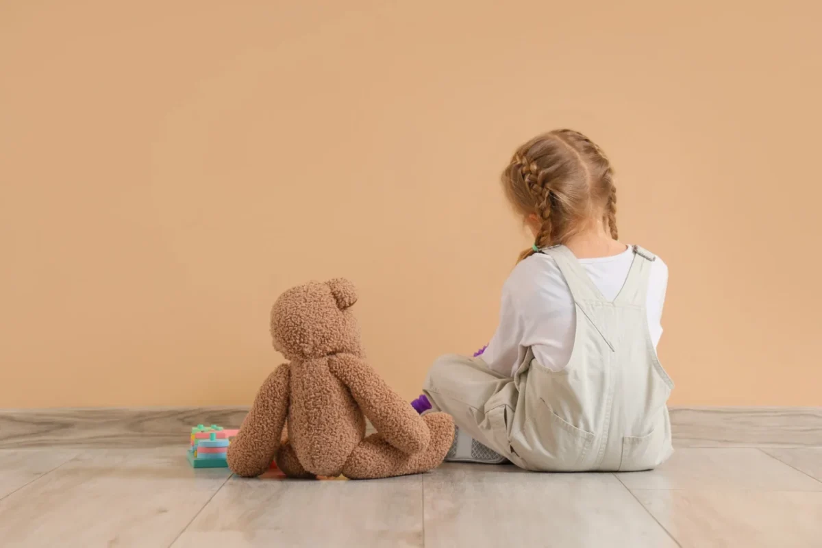 Holčička s plyšovým medvědem, zády k nám.