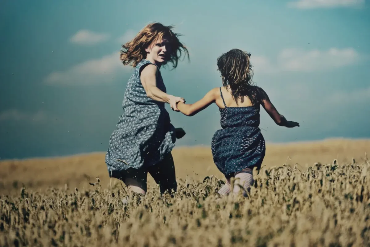 Aňa Geislerová s holčičkou utíkají po poli.