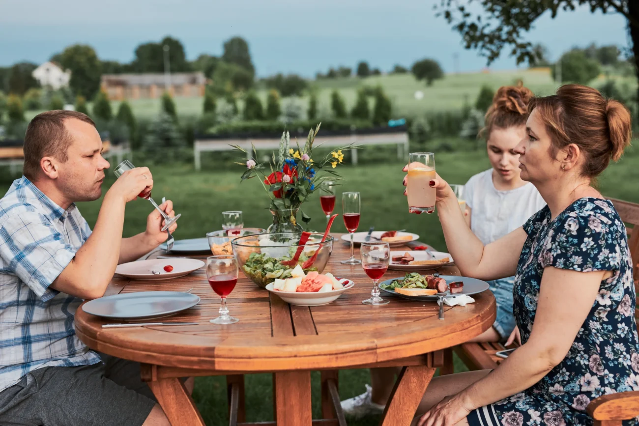 shutterstock_1839327088-2 | TVGURU.cz Rodina sedí venku a dává si jídlo.