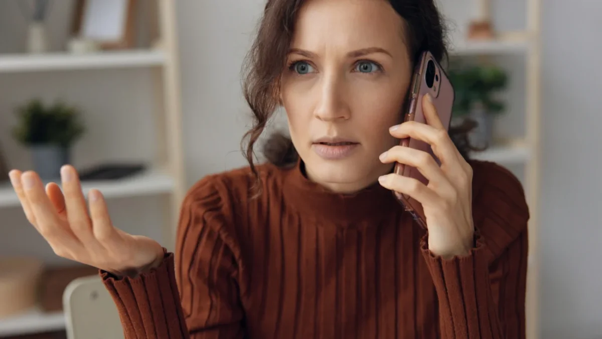 Šokovaná žena telefonuje.
