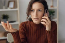 Šokovaná žena telefonuje.