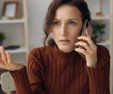 Šokovaná žena telefonuje.