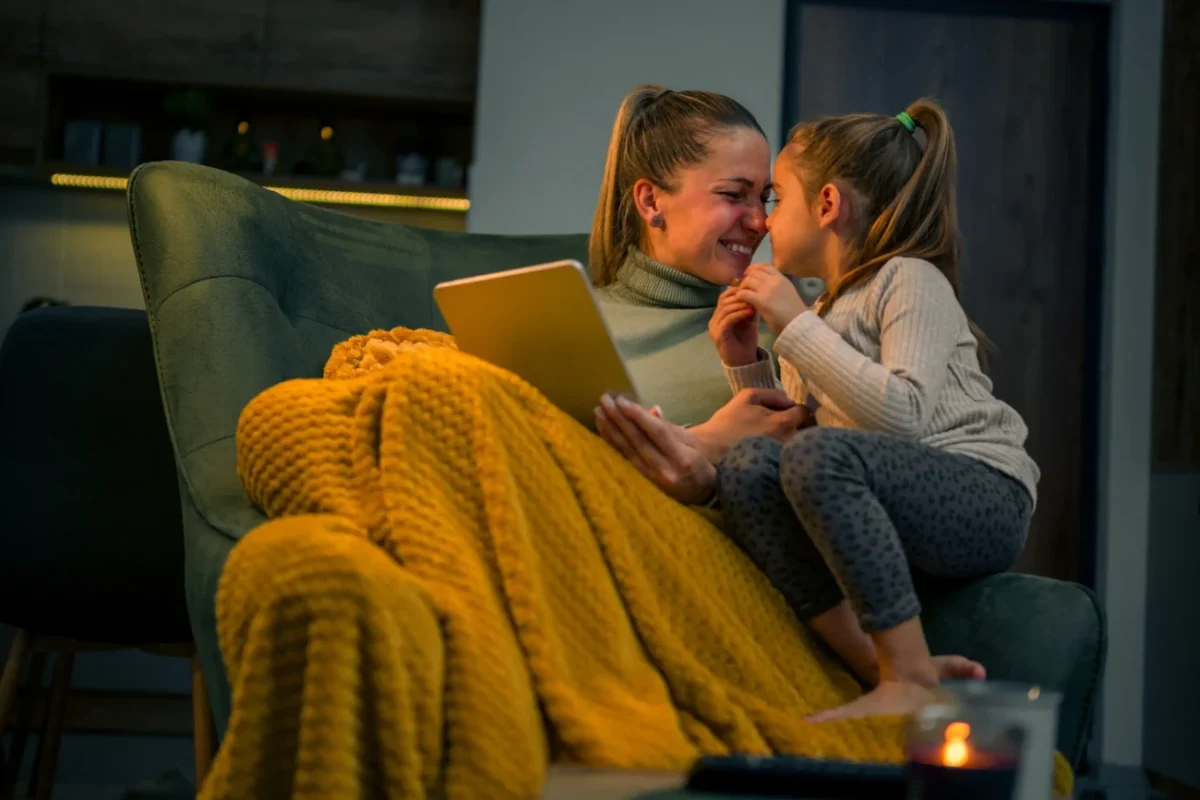 Maminka s dcerou sedí doma přikryté dekou.