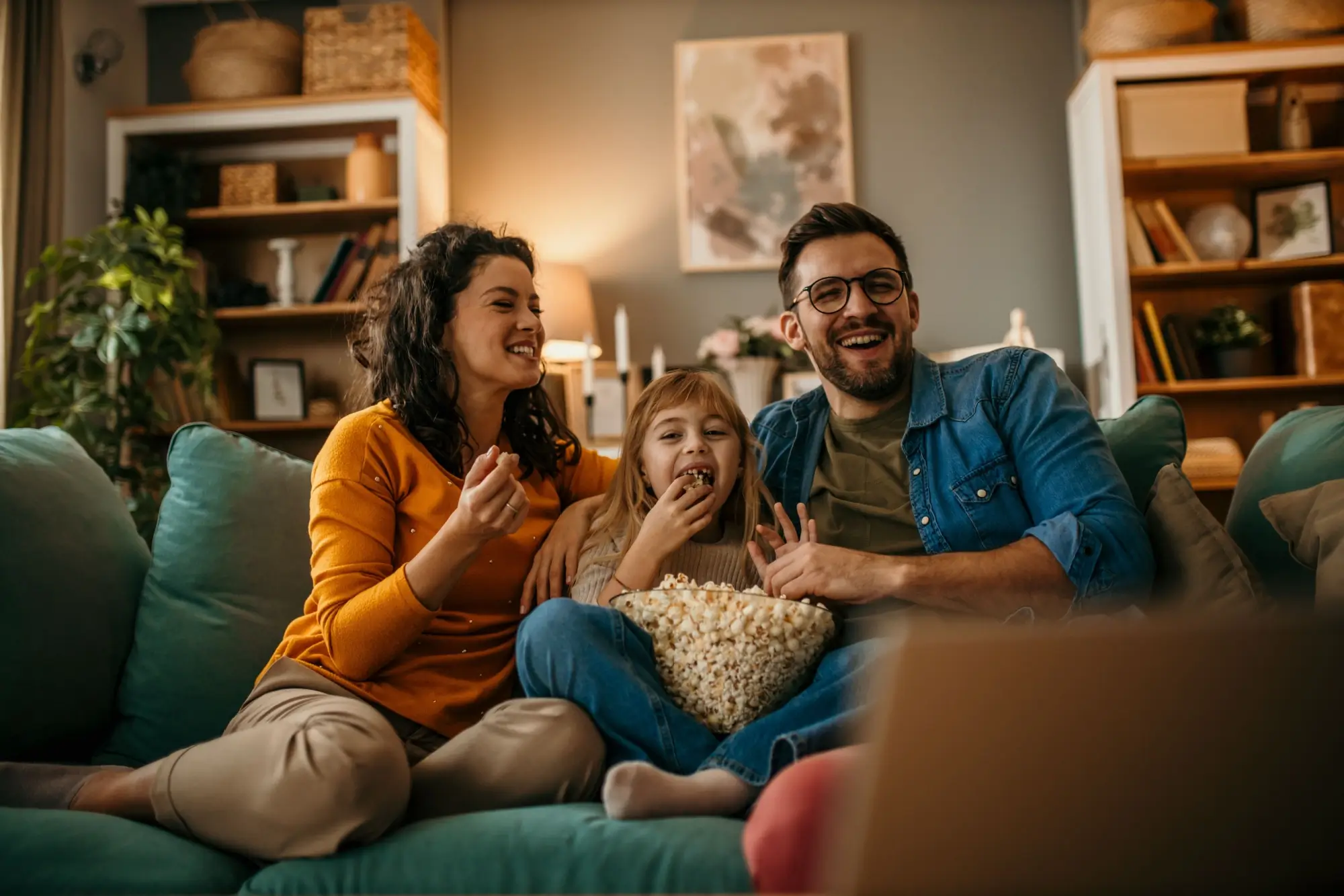 Shutterstock_2489421783 | TVGURU.cz veselá rodina s popcornem na gauči společně sleduje televizi