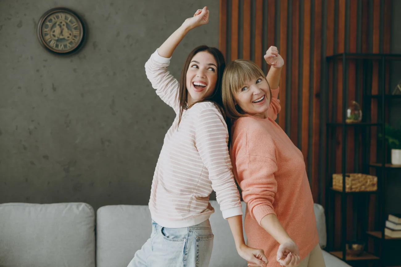 shutterstock_2288095335-2 | TVGURU.cz Ženy jsou šťastné a tančí v obýváku.