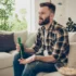 Muž v ruce drží pivo a nechápavě kouká na televizi.