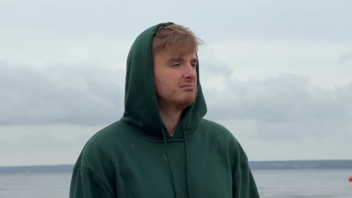 Muž má na hlavě kapuci a tváří se ustaraně.