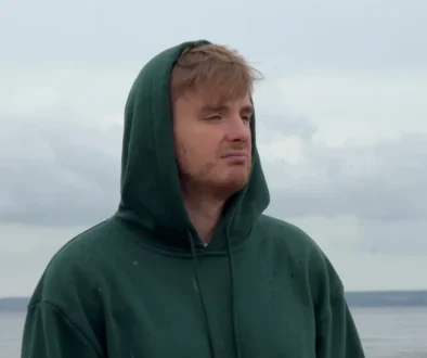 Muž má na hlavě kapuci a tváří se ustaraně.