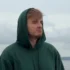 Muž má na hlavě kapuci a tváří se ustaraně.
