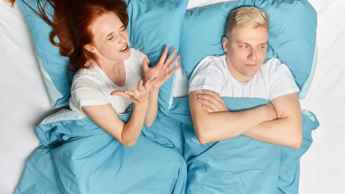 Žena a muž vedle sebe leží naštvaní v posteli.