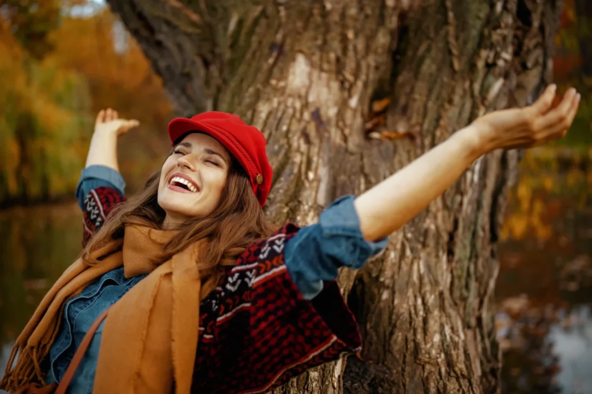 Žena opírající se šťastně o strom.