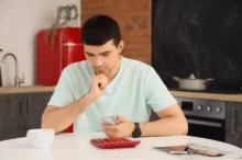 Muž sedící u stolu a přepočítávající peníze.